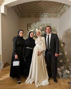 three people standing next to each other in front of a christmas tree with decorations on it