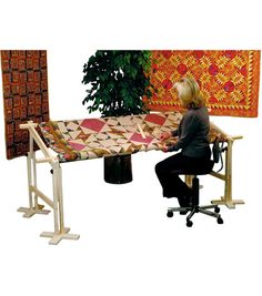 a woman sitting at a table with a quilt on it