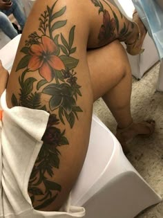 a woman with tattoos on her back sitting on a toilet