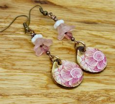 These handmade pink floral earrings have a casual and rustic look.  The handmade earrings are statement dangles.  I added a rose crystal to a pink and white bell shaped floral to create what looks like a blossom with  a pattern of flowers on a tear shaped ceramic.   They hang 2 inches from curve in ear wire to bottom of ceramics.  Surprisingly light  earrings to wear! The art jewelry has ceramics are by Scottish artisan Grubbi.   You can see additional earrings in my shop by visiting http://www. Handmade Pink Teardrop Flower Earrings, Handmade Pink Bohemian Flower Earrings, Handmade Bohemian Pink Flower Earrings, Pink Handmade Vintage Flower Earrings, Handmade Pink Vintage Flower Earrings, Bohemian Pink Earrings With Flower Charm, Bohemian Pink Earrings With Handmade Flowers, Handmade Vintage Pink Flower Earrings, Pink Bohemian Flower Drop Earrings