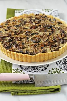 a mushroom and cheese quiche on a white plate with a green place mat next to it