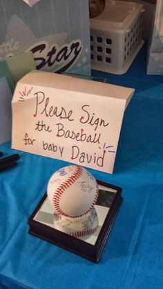 a baseball sits on top of a table with a sign that says please sign the base ball for baby david