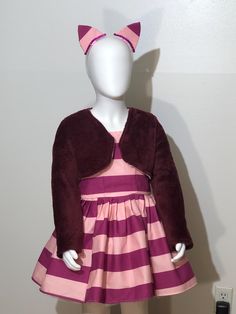 "We're all mad here" Dazzle in this fun Cheshire Cat inspired costume set.  Costume set includes the dress, short jacket and headband.   The dress is above the knee and made of a plum and pink stripe cotton fabric with zipper back. Dress skirt is knee length with matching plum and pink stripe fabric with a lining and crinoline underskirt to give the dress its fullness.   The costume comes with a matching headband with sequin trim and a lush fleece fabric jacket in a deep plum color. ++  PLEASE CHECK THE SIZECHART PROVIDED IN THE LISTING PICTURES.  If you have any questions, please contact me directly. Please be sure to read our policies prior to your purchase.   Haydee's Boutique has a no refund policy.  Customers are responsible for reviewing the product listing information and size chart Cheshire Cat Costume, We're All Mad Here, Cat Costume, Deep Plum, Stripe Fabric, Product Listing, Cat Costumes, Cheshire Cat, Matching Headband