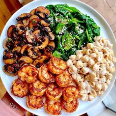 a white plate topped with pasta, shrimp and spinach next to broccoli