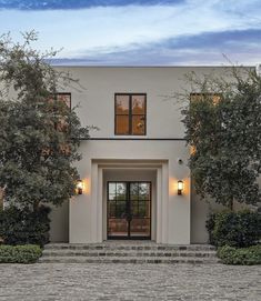 a large white house with lots of windows and trees in front of the entrance to it