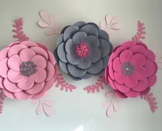 three large paper flowers on a white wall