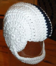 a crocheted hat is sitting on top of a wooden table with a black and white stripe