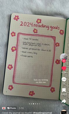 an open book with flowers on it and the words reading goals written in pink ink