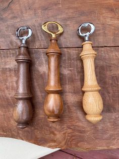 three different sized wooden objects hanging on a wood board with metal handles and rings attached to them