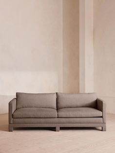 a couch sitting on top of a hard wood floor next to a white wall in an empty room