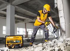 a man in yellow shirt and helmet holding a chainsaw while standing next to rubble