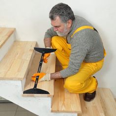 a man in yellow pants sanding down some stairs with a hammer and an orange mitt