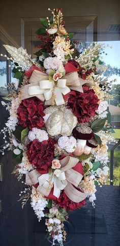 a christmas wreath with red, white and gold flowers hanging from the side of a door