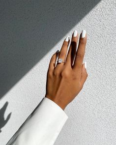 a woman's hand with white manicured nails and ring