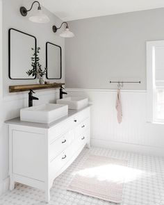 a white bathroom with two sinks and mirrors