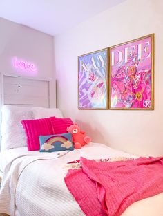 a bedroom with two pictures on the wall and a pink bed in front of it