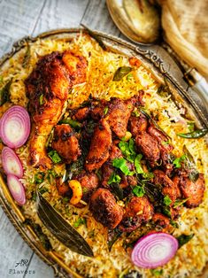 chicken and rice dish with onions on the side, served in an ornate silver platter