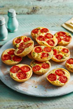 small tarts with tomatoes and cheese on a plate next to some salt shakers