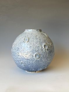 a gray vase sitting on top of a white table