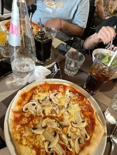 a pizza sitting on top of a white plate next to a glass filled with liquid