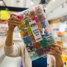 a woman holding up a plastic box filled with gummy bears