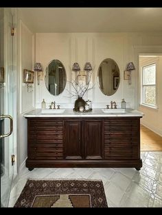 a large bathroom with double sinks and mirrors on the wall next to a rug in front of it