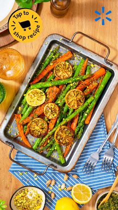 a pan filled with carrots and asparagus on top of a wooden table