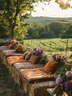 a row of hay bales with pillows and flowers on them in front of a field