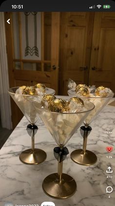 three martini glasses filled with chocolates on top of a marble counter