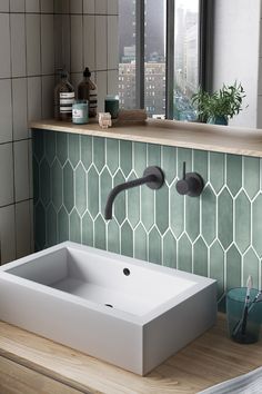 a white sink sitting on top of a wooden counter next to a green tiled wall