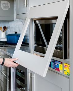 a woman is opening the door to a microwave in a kitchen with stainless steel appliances