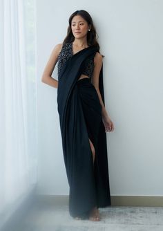 Elevate your evening look effortlessly with this pre-stitched sari. It features a knot-drape skirt in shimmery black georgette with an attached drape and a sleeveless beaded blouse boasting a plunging v-neckline. This ensemble is lightweight and effortlessly chic, making a striking statement perfect for cocktail parties or evening festivities under the stars. Black Georgette Draped Saree, Black Draped Georgette Saree, Evening Party Wear Pre-draped Sleeveless Saree, Pre-draped Side Open Saree For Party, Black Draped Saree With Sheer Dupatta, Black Bollywood Style Pre-draped Saree, Black Bollywood Pre-draped Saree, Black Pre-draped Saree With Sequins, Black Pre-draped Party Saree