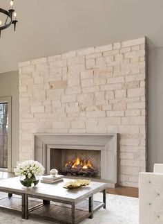 a living room filled with furniture and a fire place under a chandelier in front of a fireplace