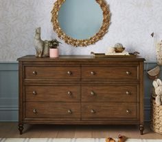 a dresser with a mirror and stuffed animals on top of it in front of a blue wall