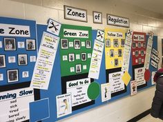 a woman standing in front of a bulletin board with pictures on it and people looking at it