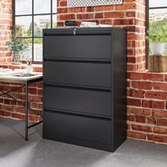 a black filing cabinet next to a brick wall