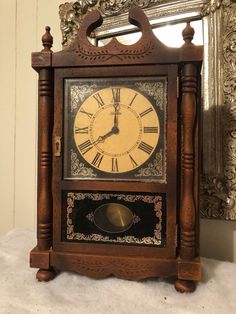 an old wooden clock with roman numerals on the front and sides, sitting in front of a mirror