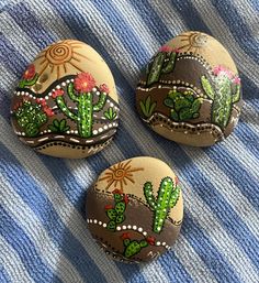 three painted rocks sitting on top of a blue and white blanket