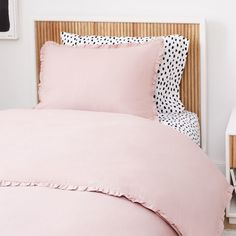 a pink bed with black and white polka dot pillows on the headboard in a bedroom