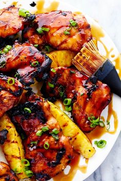 grilled chicken and pineapples on a white plate with a brown spatula