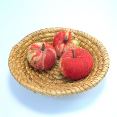 three red apples sitting on top of a wicker bowl