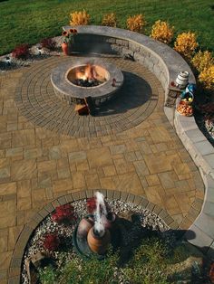 two dogs are sitting in the middle of a brick fire pit and surrounded by flowers