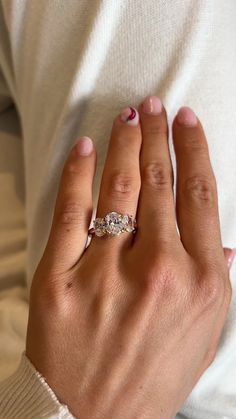 a woman's hand with a ring on top of her left hand and a white sweater