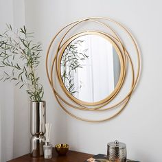 a round mirror on the wall next to a table with a vase and other items