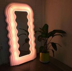 an illuminated mirror sitting next to a potted plant