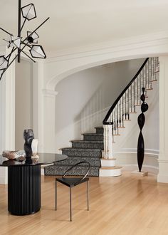 an elegant staircase in the middle of a living room with black and white decor on it