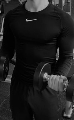 a man is holding two dumbs in his hands while standing next to a barbell