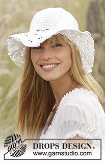 a woman with long blonde hair wearing a white hat and smiling at the camera, outdoors