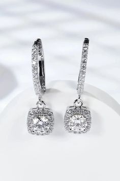 Adored Moissanite Huggie Drop Earrings Elevate your elegance with the Adored Moissanite Huggie Drop Earrings. These stunning earrings are not just accessories, but a statement of sophistication and timeless beauty. Key Features: Crafted from 925 sterling silver with a luxurious platinum plating for added durability and shine. Each earring features a 1-carat moissanite stone, totaling 2 carats, and accented with dazzling zircon stones. Geometric modern design that complements both casual and form Moissanite Halo Design Earrings, Moissanite Halo Earrings, Elegant Dangle Hoop Earrings With Halo Design, Dangle Hoop Earrings With Halo Design In Cubic Zirconia, Diamond White Dangle Earrings With Halo Design, Formal Silver Hoop Earrings With Halo, Stunning Earrings, Silver Drop Earrings, 2 Carat