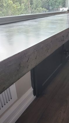 a counter top in front of a window with wood flooring and white paint on it